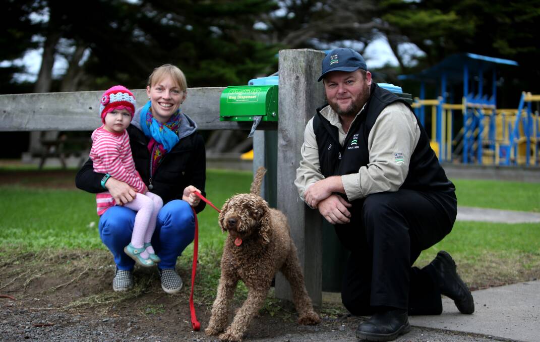 Responsible: Dog owner Jess Clift with daughter Freya, Jaffa the labradoodle, and Moyne Shire ranger Colin McKane with one of the bag dispensers. Picture: Amy Paton
