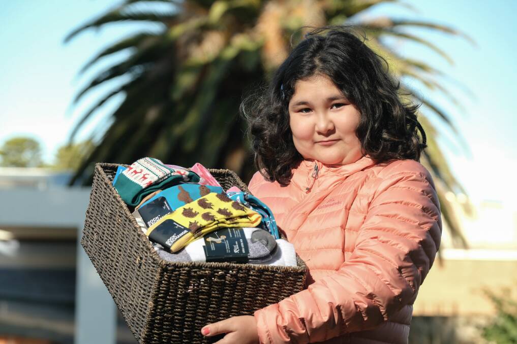 Cosy: Sofia Osmonova, 11, with some of the socks already donated ahead of a sock collection drive on Saturday for newly-arrived people from Ukraine. Picture: Chris Doheny