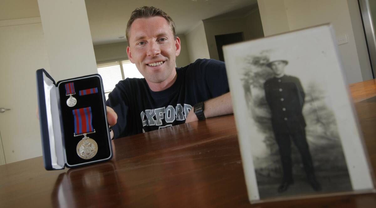 HONOURED: Jason Kelly back in 2013 with a photo of his grandfather, Constable James Brewis, and a medal belonging to him. Constable Brewis' grave now has a headstone thanks to the work of his grandson. 