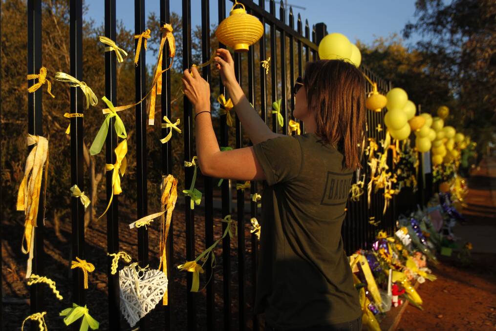 TRAGEDY: A resident ties a yellow ribbon to the fence at Leeton High School after Stephanie Scott's death.