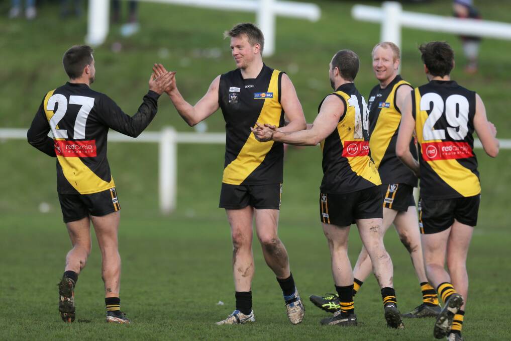 Nearly there: Tiger Jet Dowie is congratulated by teammates after kicking his 99th goal of the 2015 season against East Warrnambool. Picture: Rob Gunstone