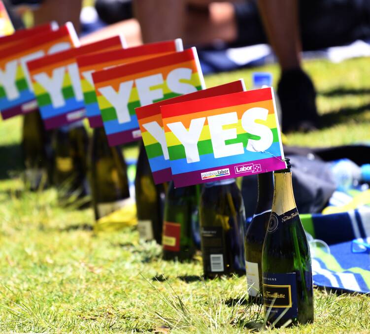 Empty bottles of champagne sit with rainbow Yes flags in them after the marriage vote result announcement during a picnic held by the Equality Campaign at Prince Alfred Park in Sydney, Wednesday, November 15, 2017. Australians have given same-sex marriage their approval with a 61.6 per cent 'Yes' vote in a voluntary survey. (AAP Image/David Moir) NO ARCHIVING