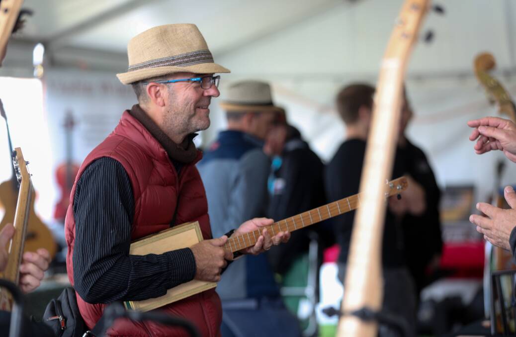 Diego Barua, from Frankston, admires the cigar box guitar in the instrument makers tent. Picture: Rob Gunstone