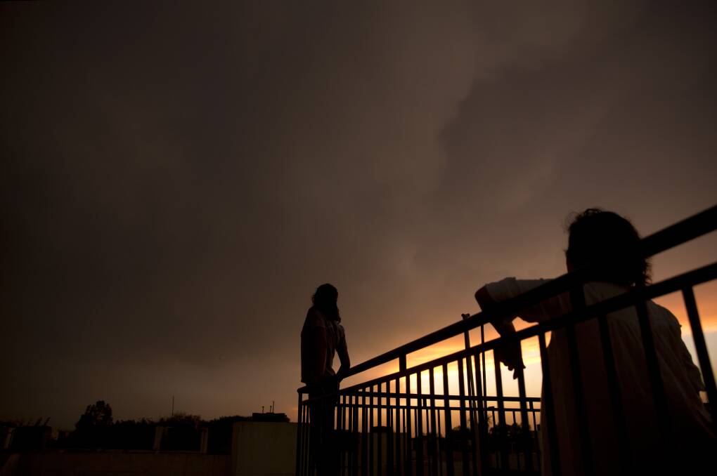 It's a big world: Indians enjoy sunset as rain clouds gather over the skyline in New Delhi, India, on Sunday night.