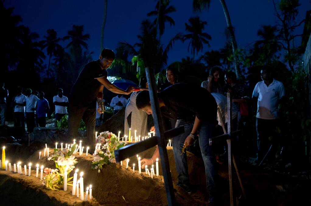 Relatives light candles after the burial of three victims of the same family, who died at Easter Sunday bomb blast at St. Sebastian Church in Negombo, Sri Lanka. Easter Sunday bombings of churches, luxury hotels and other sites was Sri Lanka's deadliest violence since a devastating civil war in the South Asian island nation ended a decade ago. (AP Photo/Gemunu Amarasinghe)