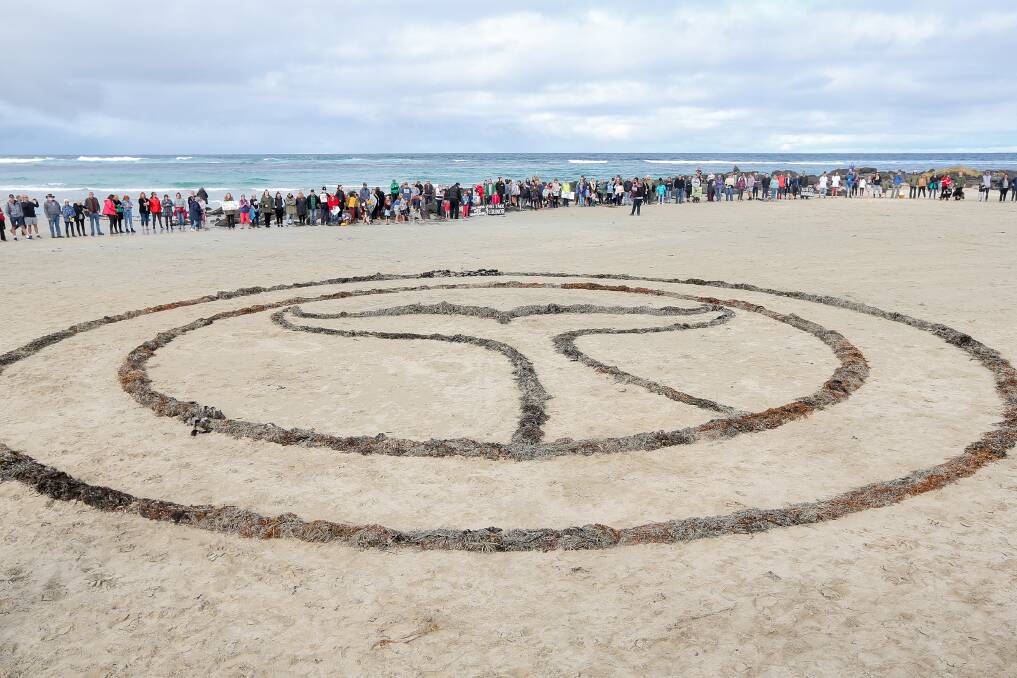 Over 100 people gathered on South Beach in Port Fairy for the Hands in the Sand protest. Picture: Christine Ansorge