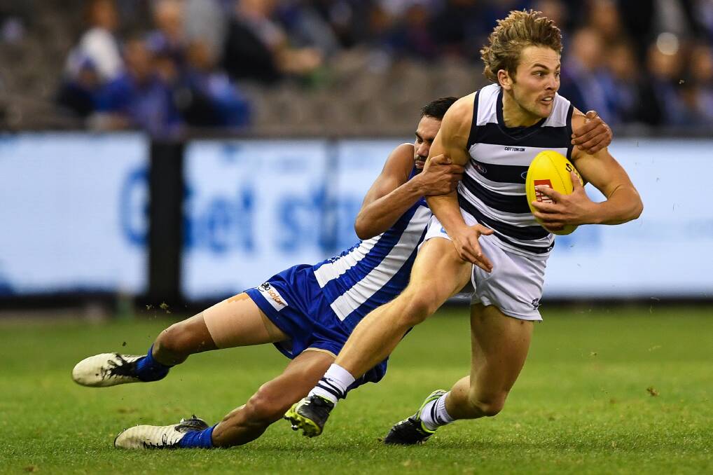 Caught: North Melbourne's Tarryn Thomas tackles Geelong's Tom Atkins in 2019. Picture: Morgan Hancock
