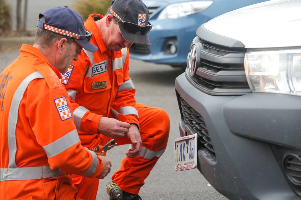 Change over: SES volunteers work on changing licence plate screws for an anti-theft version. Picture: Rob Gunstone