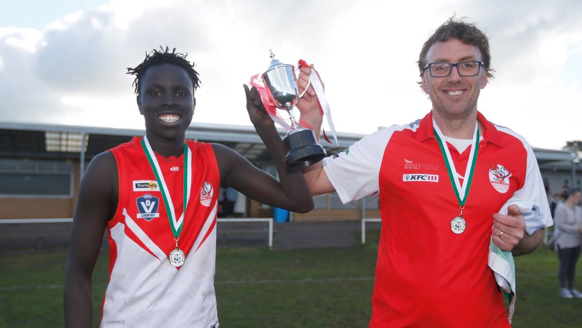 WINNERS: South Warrnambool's captain Mojwok Akoch and coach Sam Stevens loft up the under 16 premiership cup. Picture: Mark Witte