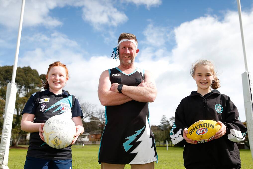 Finals fever: Student Rose Beasley, 12, and Matilda Curran, 10, presented principal Ben van de Camp, with a netball dress and headband to wear at assembly this morning in anticipation of the grand final on Saturday. Picture: Mark Witte