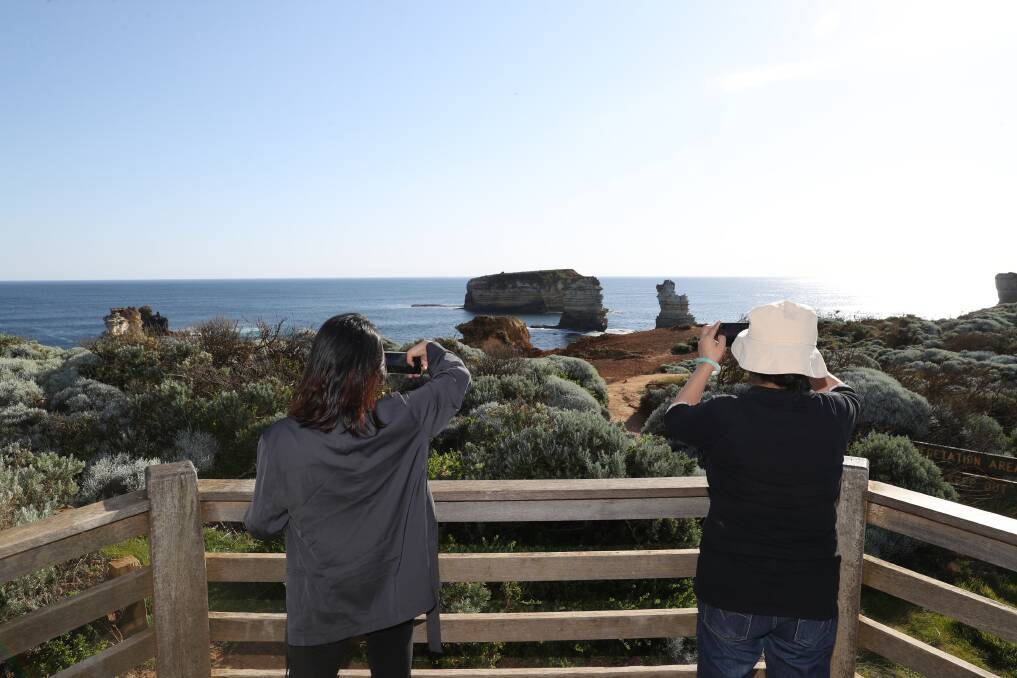 Tourists take photos of the Bay of Islands, where the Great Ocean Road turns inland. Picture: Mark Witte