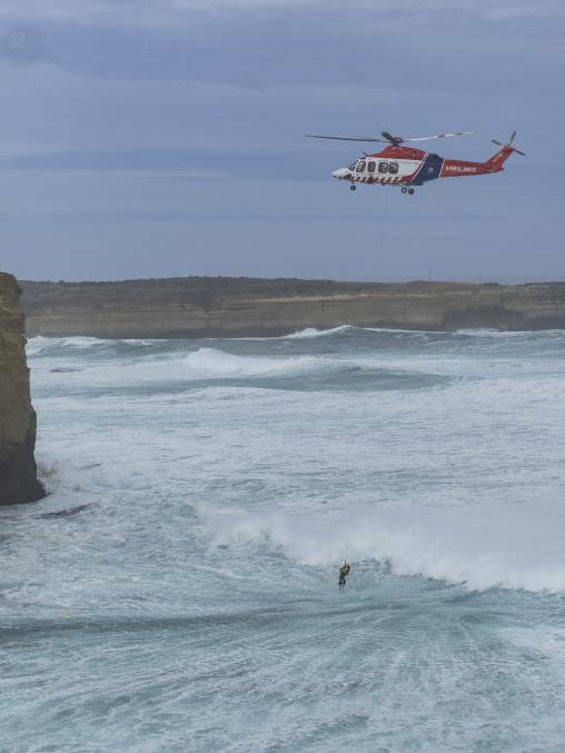 MISSION: HEMS4 winches the third lifesaver to safety from the heavy seas near Port Campbell on Sunday where two men died trying to save a tourist. Picture: Ian McCauley