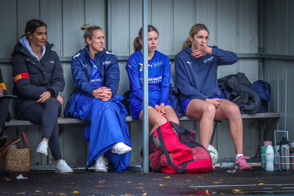 Hamilton Kangaroos' players try and keep warm on the bench during a cold, wet day at Melville Oval in 2023. Picture by Justine McCullagh-Beasy 