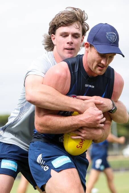 Warrnambool teenager Reggie Mast wraps Geelong premiership player Jed Bews in a tackle at Cats' training on Monday night. Picture by Anthony Brady 