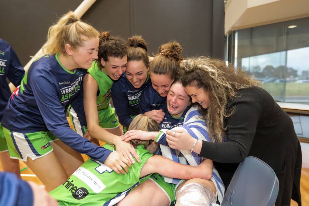 Getting around teammate: Mermaids' players celebrate the 2018 grand final win with injured Molly McKinnon on the bench. 