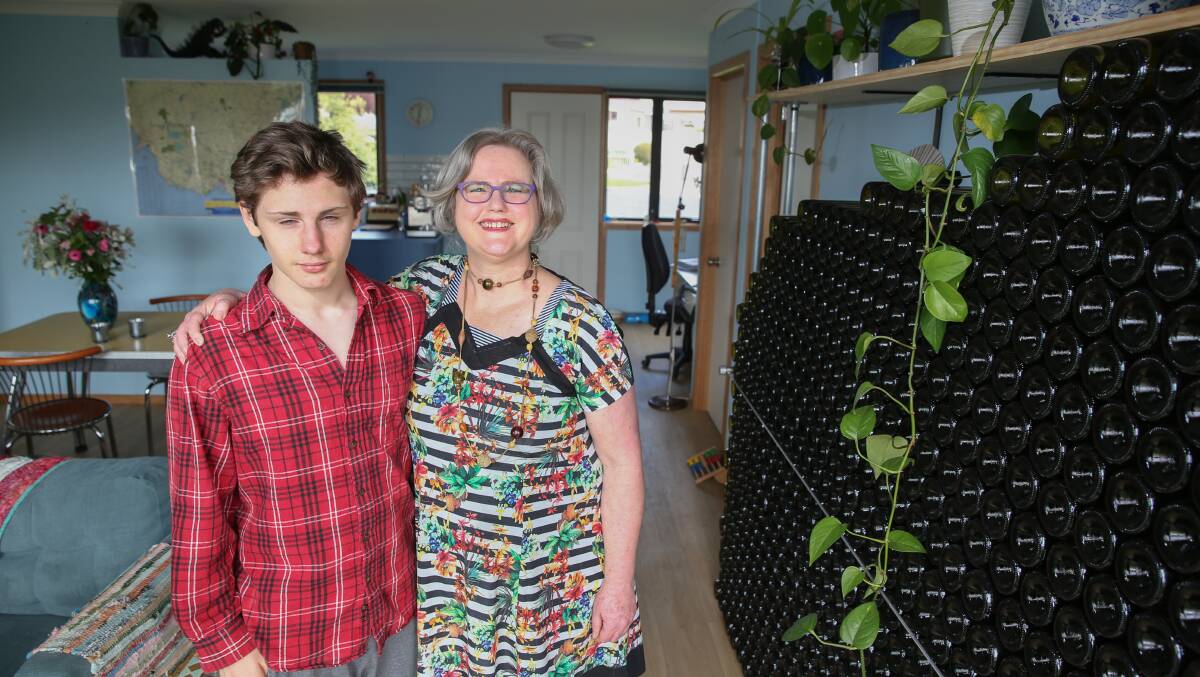 Sophia MacRae and Derek in front of their wine bottle wall which is a massive contributor to warming their house. Picture: Mark Witte.