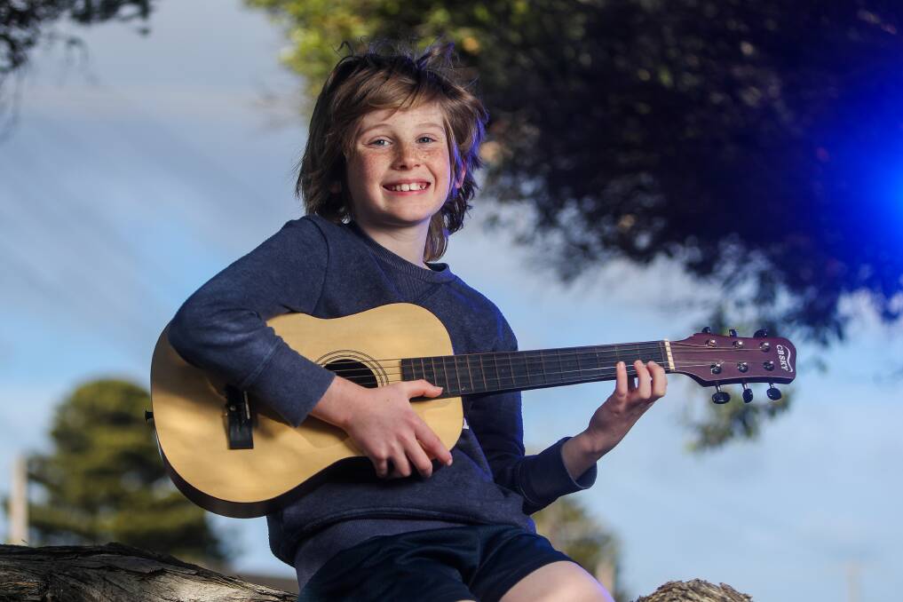 POSITIVE VIBES: Cooper OKeefe Nagorcka, 10, wrote his own song for the guitar and plays it outside of his house to cheer up people walking by. Picture: Morgan Hancock 