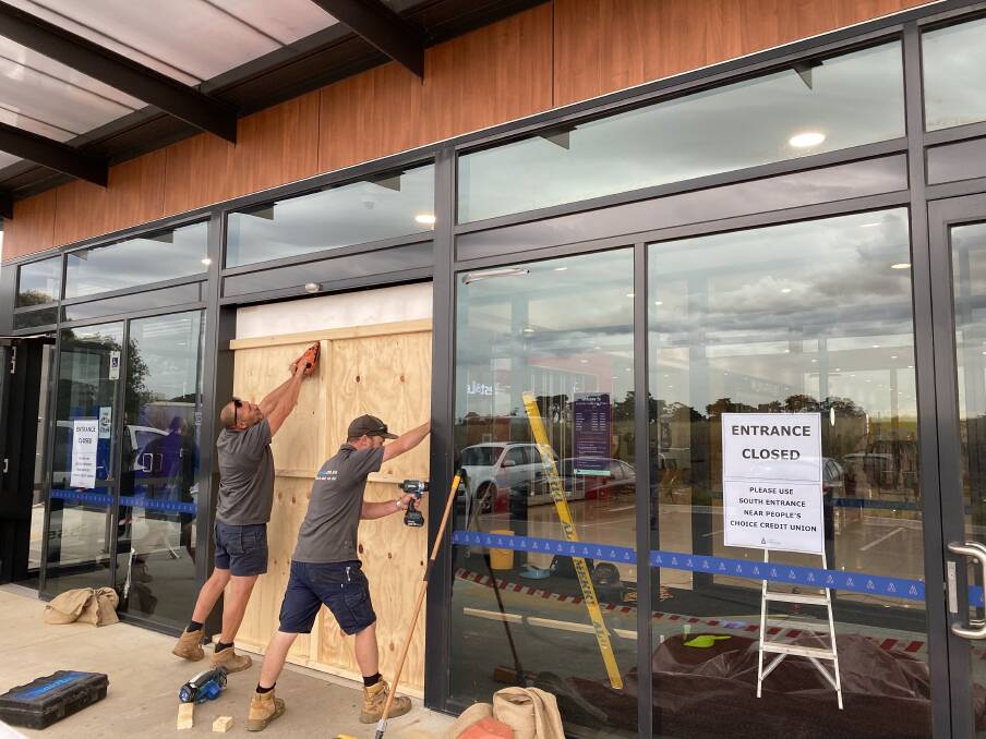 Repair: Ahmed Ebeid and Dan Edwards work to secure one of three glass doors that were smashed when a car drove through Gateway Plaza and out another set of doors.