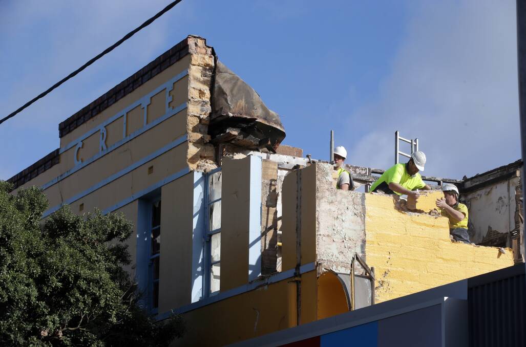 Workers demolish the building after the fire.