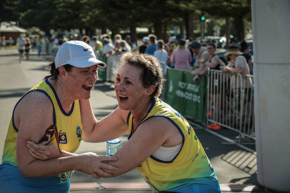 Jodie Irving (left) greets Kaylene Duerden as she comes across the finish line of the Surf 'T' Surf on Sunday having achieved her goal of finishing after undergoing cancer treatment last year. Picture by Sean McKenna