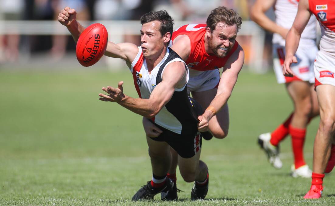 DIGGING IN: Koroit's Taylor Mckenry handballs under heavy duress from a South Warrnambool opponent. Picture: Morgan Hancock
