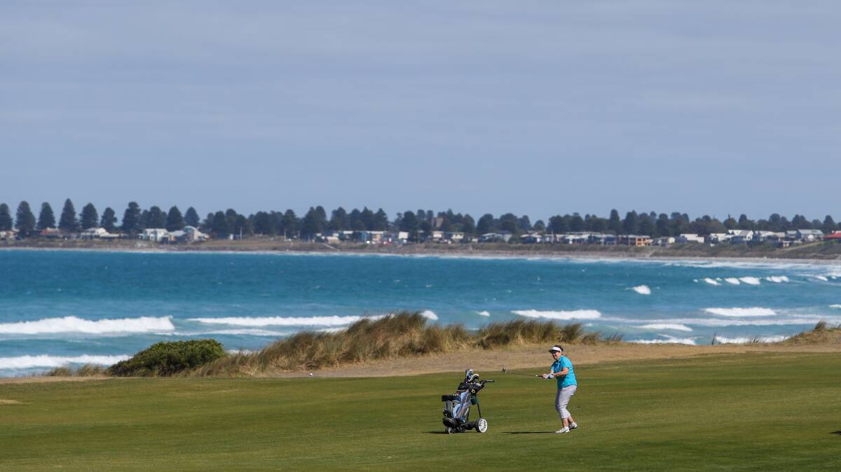 SCENIC: Helen Dwyer hits the ball towards the green at Port Fairy Golf Club with the seaside town in the distance. Picture: Morgan Hancock 