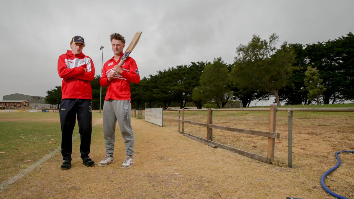 NOT HAPPY: Dennington cricketers Charlie and Jack Noonan in front of a blank space where a recent sponsor sign was stolen. Picture: Chris Doheny