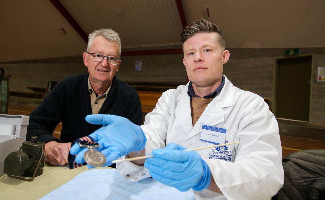 Warrnambool's Stuart Bethune gets a lesson on how to clean and care for his grandfather's WW1 bravery medal from Melbourne University Grimwade Centre PhD student Evan Tindal. Picture: Rob Gunstone