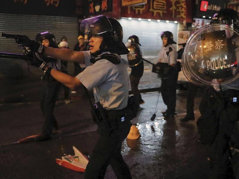 A Hong Kong police officer points his gun at protesters.