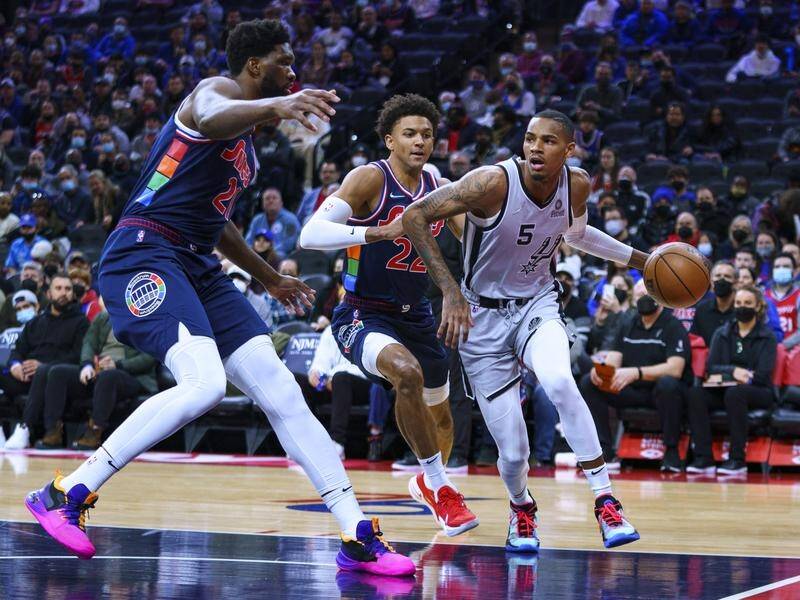 Dejounte Murray (r) drives to the basket against the 76ers Joel Embiid (l) and Matisse Thybulle.
