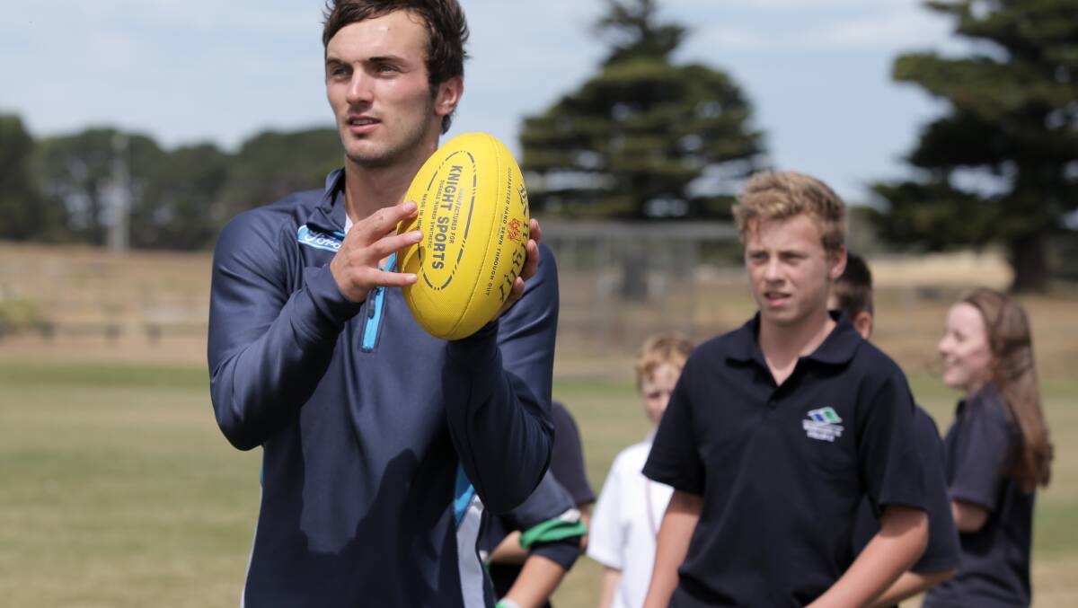 Geelong's George Burbury watches Warrnambool College students go through their paces during a handball drill. 