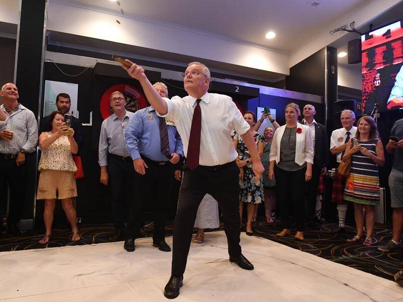 Prime Minister Scott Morrison plays two up at the Cazalys Palmerston Club in Darwin.