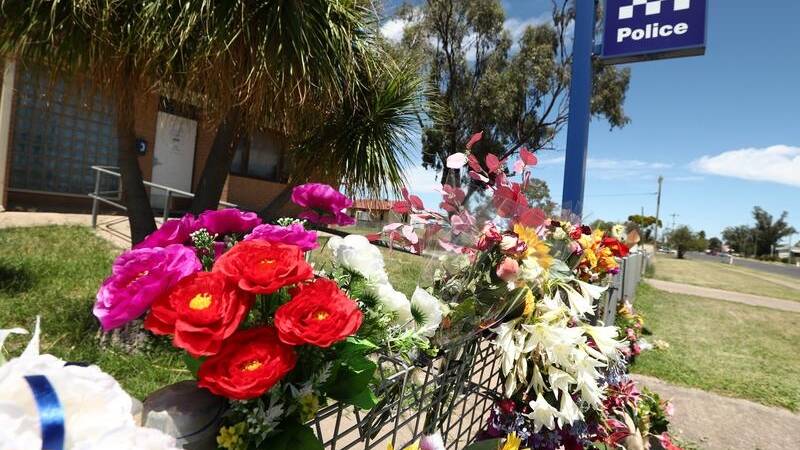 Tributes to the Wieambilla shooting victims are seen outside the Tara Police Station in Queensland. (JASON O'BRIEN/AAP PHOTOS)