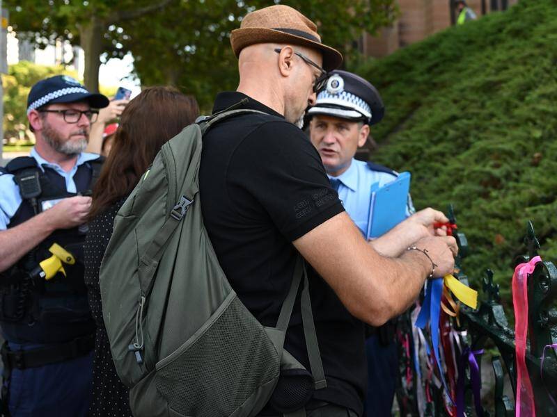 Police speak to a man removing ribbons at St Mary's Cathedral at the mass for Cardinal George Pell. (Dean Lewins/AAP PHOTOS)