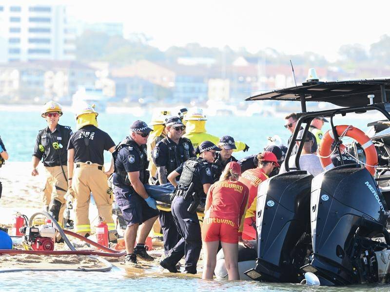 Emergency workers move a body from the site of a helicopter crash near Sea World on the Gold Coast. (Dave Hunt/AAP PHOTOS)