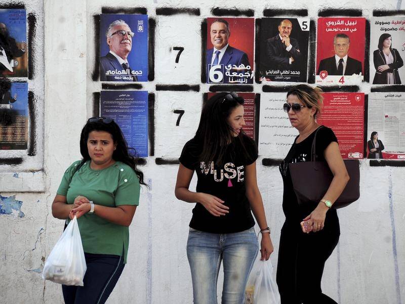 Women walk past candidates' posters in Tunis ahead of Tunisia's presidential election.