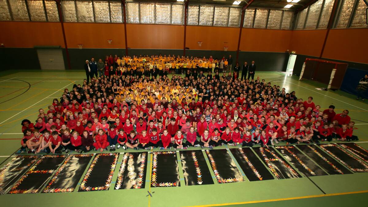 Warrnambool Primary School pupils create an Aboriginal flag on the school gym floor as part of Reconciliation Week.