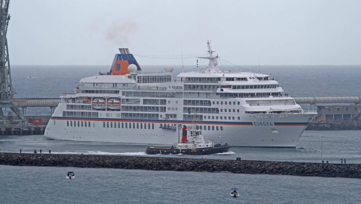 The MS Europa is guided by a tug into Portland harbour