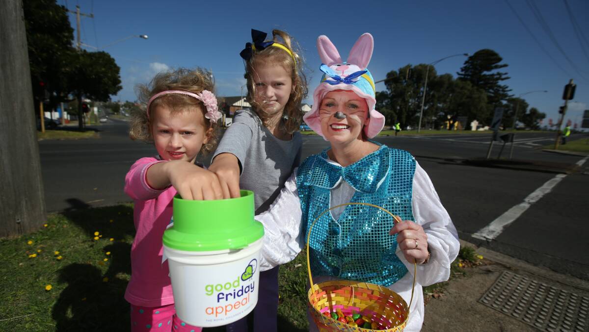 Warrnambool sisters Lily, 4, and Ruby O’Brien, 6, chip in their Tooth Fairy change to the Good Friday Appeal — with a chocolate egg their reward from Easter Bunny helper Gayle Payne.