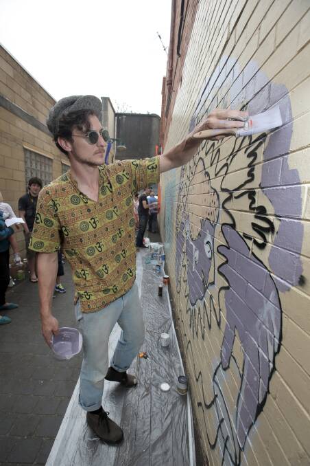 Warrnambool artist Thomas Pendergast adds colour to a mural in Ozone Lane. 