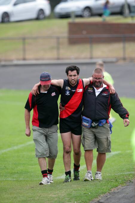 Cobden captain Paul Foster is assisted from the ground after injuring his right knee on Saturday. 