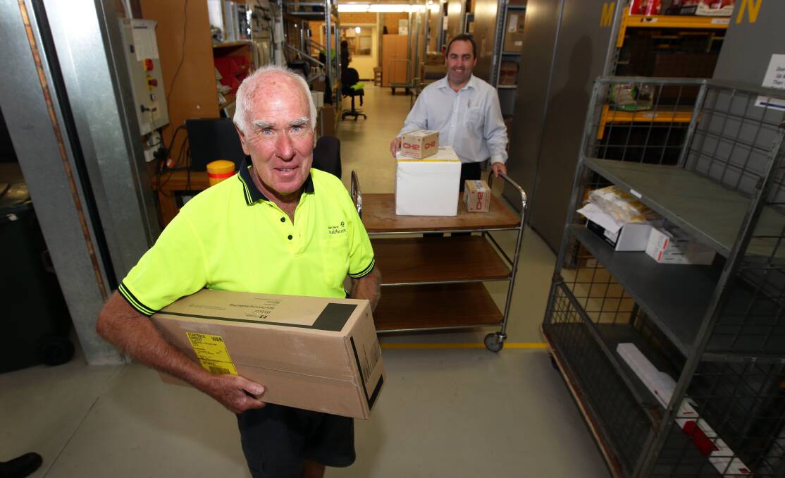 Noosa’s Philip Waugh (left) prepares for a delivery during his annual volunteering at Warrnambool Base Hospital with supply department deputy manager Shane Grundy. 