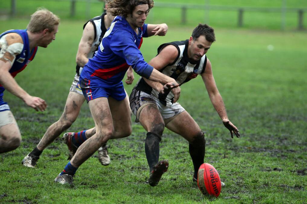 Camperdown’s Aaron Sinnott gets himself between Terang Mortlake’s Matthew Arundell and the ball in heavy conditions at Terang Recreation Reserve on Saturday. 