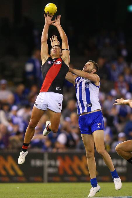 Essendon rookie Zach Merrett flies above opponent Sam Gibson in his AFL debut against North Melbourne. 