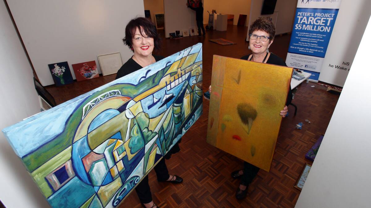 Auction organisers Liza McCosh (left), with a painting by Mem Taberner called Warrnambool on Good Day? and Ann Krause holding a painting by Ron Quick called Paddocks Edge. 