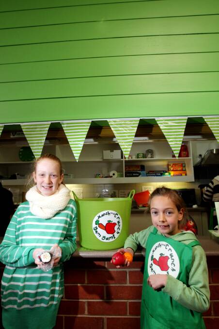 Ten-year-old Sarah Ewing samples a tuna sushi from her lunch order while Scarlett Sanelli, 7, who won the Green Canteen logo competition, helps herself to some fruit.   140718LP04 Picture: LEANNE PICKETT