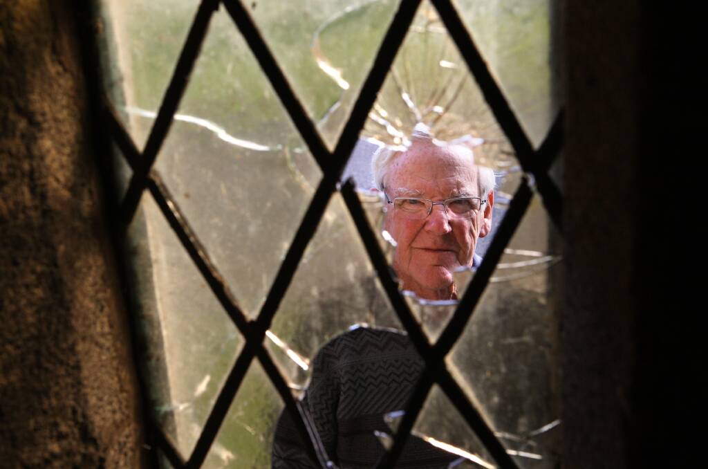 Rector’s warden at St John’s Anglican Church in Port Fairy, Kevin Harris, inspects damage committed by vandals to stained glass and leadlight windows in the historic 1850s
bluestone building. 