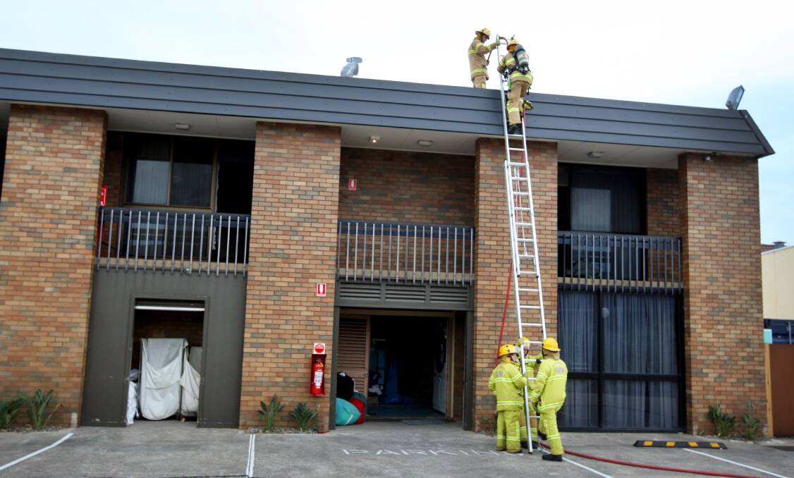 Firefighters access the roof of the Mid-City Motel to tackle yesterday’s fire. 140619LP52 Picture: LEANNE PICKETT