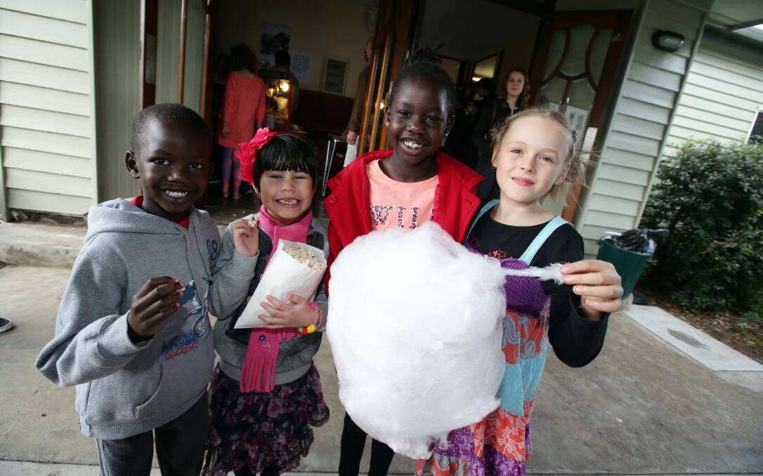 Mali Lual, 5 (left), Ruby Rushbrook, 5, Cigi Lual, 7, and Olive Adams, 8, enjoy popcorn and fairy floss at yesterday’s refugee support gathering. 140622DW27 Picture: DAMIAN WHITE
