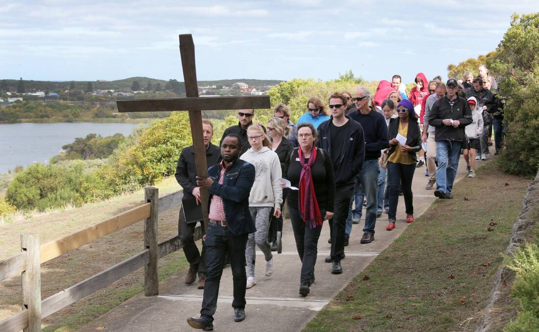 Jethro Oluwabusola, from Warrnambool Uniting Church, leads the Way of the Cross walk yesterday. 150403RG09 Picture: ROB GUNSTONE